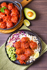 Beef meatballs in tomato sauce with rice, mashed avocado and coleslaw. View from above
