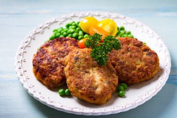 Fish burgers with vegetables on white plate. Fish patties or cakes