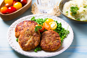 Fish burgers with vegetables on white plate. Fish patties or cakes