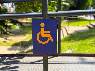 Accessibility sign on metal fence in outdoor area. Concept of inclusion, equality, and universal...