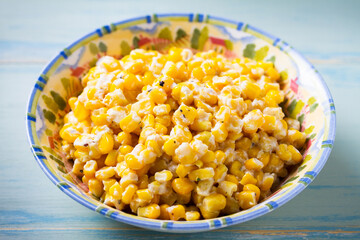 Delicious buttered sweet corn in bowl on blue wooden background