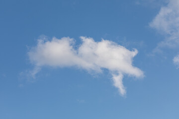 Single small white cloud against clear blue sky
