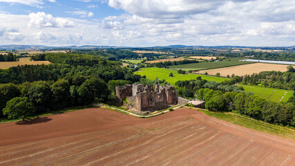 Historic Norman castle ruin surrounded by farmland and forest in Herefordshire, England