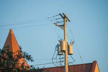 Wooden utility pole with power lines and transformer at sunset