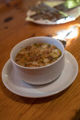 Soup with croutons in a cup with a saucer on a wooden table.
