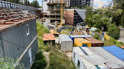 Construction site of modern high-rise residential buildings with a tower crane and temporary containers in the foreground