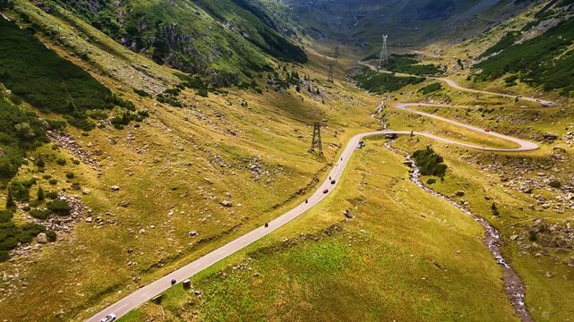 Cars and motorcycles move by the wavy highway in the mountains. Drone footage above the stunning dangerous Transfagarash highway in Romania.