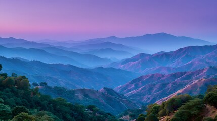Obraz premium A vast vista of layered mountain ranges bathed in soft, twilight hues of purple and blue, showcasing a serene and tranquil mountain landscape.