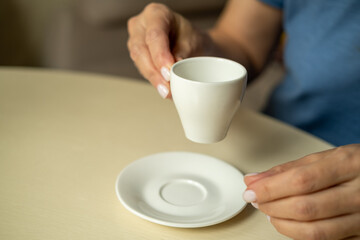  Close up of female hands holding little white cup of tea or coffee