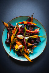 Grilled carrots, beets, asparagus, and onions on a blue plate, high angle view.
