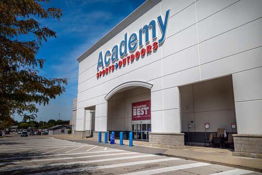O&rsquo;fallon, IL&mdash;Aug 27, 2025; strip mall store displaying red and blue academy sports and outdoor branded sign with anti vehicle barriers in front of the doors.