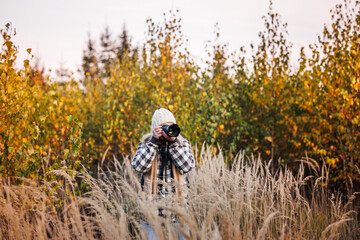 Female photographer with camera enjoying creative joy while taking pictures in autumn nature