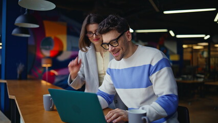 Businesspeople talking virtual meeting looking laptop colourful office closeup