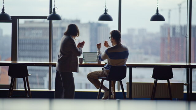 Emotional teammates watching computer celebrating victory in contemporary office - Powered by Adobe