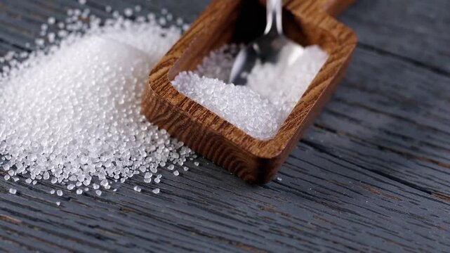 crystals crystalline structures shallow salt sodium chloride in scoop spoon utensil tool on dark gray grey table surface background 