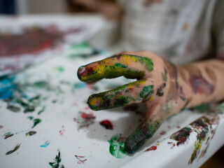 close-up of a child's fingers covered in colorful paints