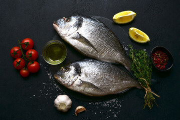 Raw dorado fish with ingredients for making : lemon, herbs, garlic, olive oil and salt . Top view with copy space.
