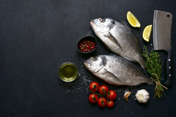 Raw dorado fish with ingredients for making : lemon, herbs, garlic, olive oil and salt . Top view with copy space.