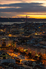 Lisbon cityscape at night with illuminated streets and 25 de Abril Bridge at sunset, Portugal