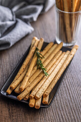 Crispy grissini breadsticks on plate on wooden table.