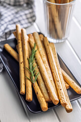 Crispy grissini breadsticks on plate on white table.
