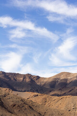 Stunning Yazd desert mountains under a clear blue sky with wispy clouds, showcasing rugged terrain and natural beauty. Ideal for travel and adventure stock photos.