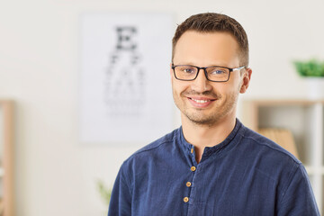 Portrait of a happy man wearing glasses standing in an optical clinic. Eyewear or optic wear for...