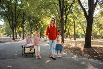 Mother and daughters walking in the park, pulling a wagon © Jelena
