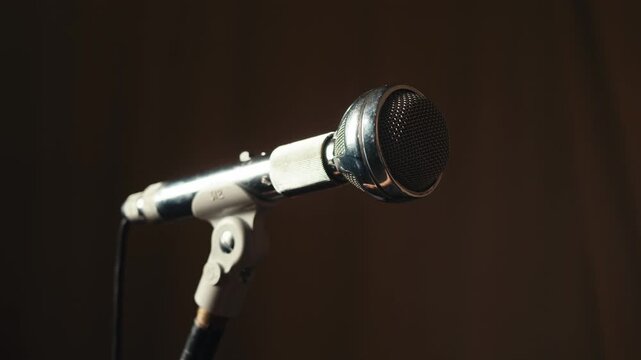 Retro microphone on studio or stage, macro of check sound, hand touch microphone. 