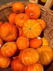 Fresh orange pumpkins in wicker basket at market