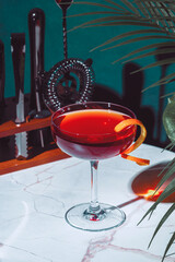 Rusty compass strong alcoholic cocktail drink with scotch whiskey, liqueur and orange twist with bar tools