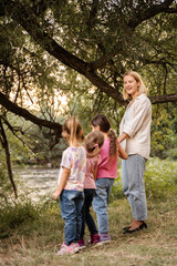 Fototapeta premium Teacher and preschool age children enjoying nature near river