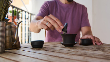 Man Enjoying Traditional Tea Ceremony Outdoors on Wooden Table