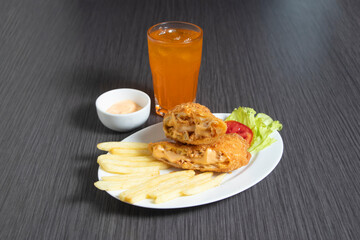 Crispy fried spring rolls meal with chili sauce, orange drink, mayo dip, fries, and salad on a white plate top view of Chinese food