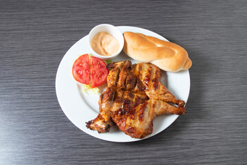 Spicy grilled BBQ chicken platter with a creamy sauce, bread, salad and fresh vegetables in plate top view of Middle Eastern Farouj