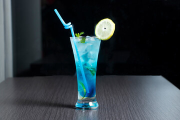 Blue Agave Margarita Cocktail with a lemon slice, mint leaves and a straw in glass side view of summer drink