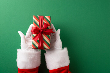 Santa's gloved hands present a festive wrapped gift with a bright red ribbon on a green backdrop, symbolizing Christmas celebrations, gift exchange, seasonal joy, and traditional holiday imagery