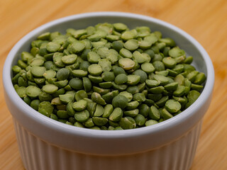 Dried Green Split Peas in a White Ramekin Bowl on a Wooden Table