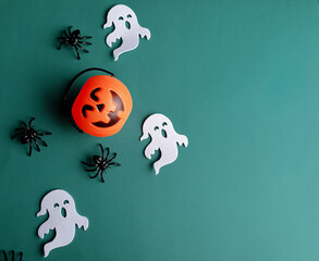 pumpkin, ghosts and spiders representing Halloween on a dark green background and with space for text