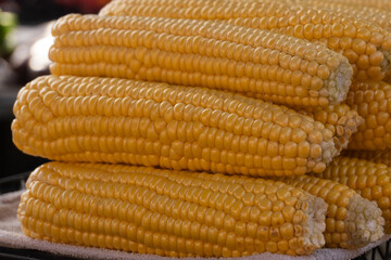 Freshly harvested corn cobs stacked at a local market showcasing vibrant colors and natural textures