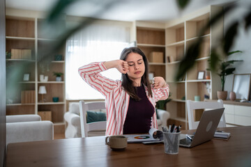 Young woman stretching while working from home office