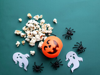 background with pumpkin and popcorn spilling, ghosts and spiders representing Halloween on a dark green background and with space for text