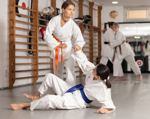 Women of European appearance practice different techniques and grips during judo training. Group training in martial arts and judo