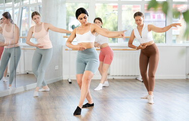 Fototapeta premium Group of young ballerinas rehearsing ballet movements in the choreography studio