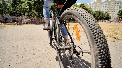 Naklejka premium A twelve-year-old girl riding her bike on a warm summer day. Bicycle wheel close up.