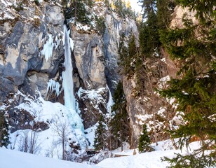 Winter waterfall cascading down icy cliff face in a mountain valley