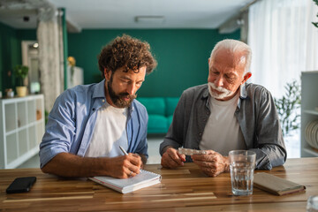 Doctor writing down medicine dosage for senior patient at home visit