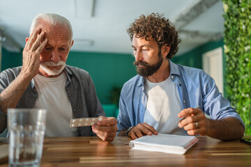 Doctor explaining medicine dosage to senior man holding pills