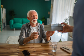 Senior man receiving gift from family member at home