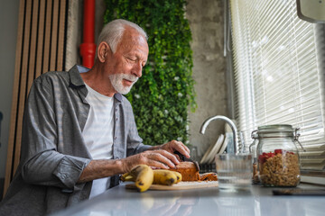 Senior man preparing breakfast with banana bread in modern kitchen